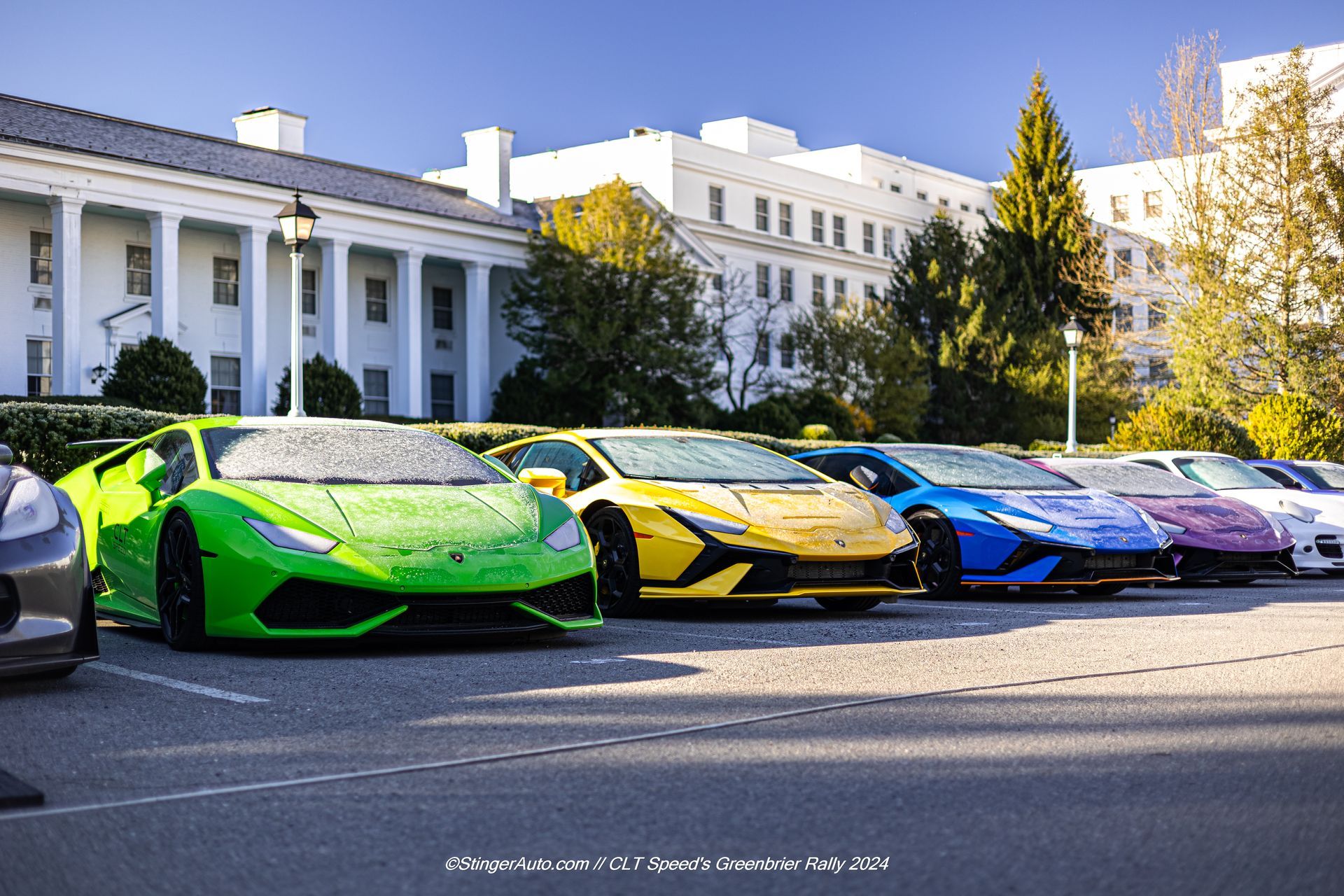 A row of lamborghini cars are parked in front of a white building