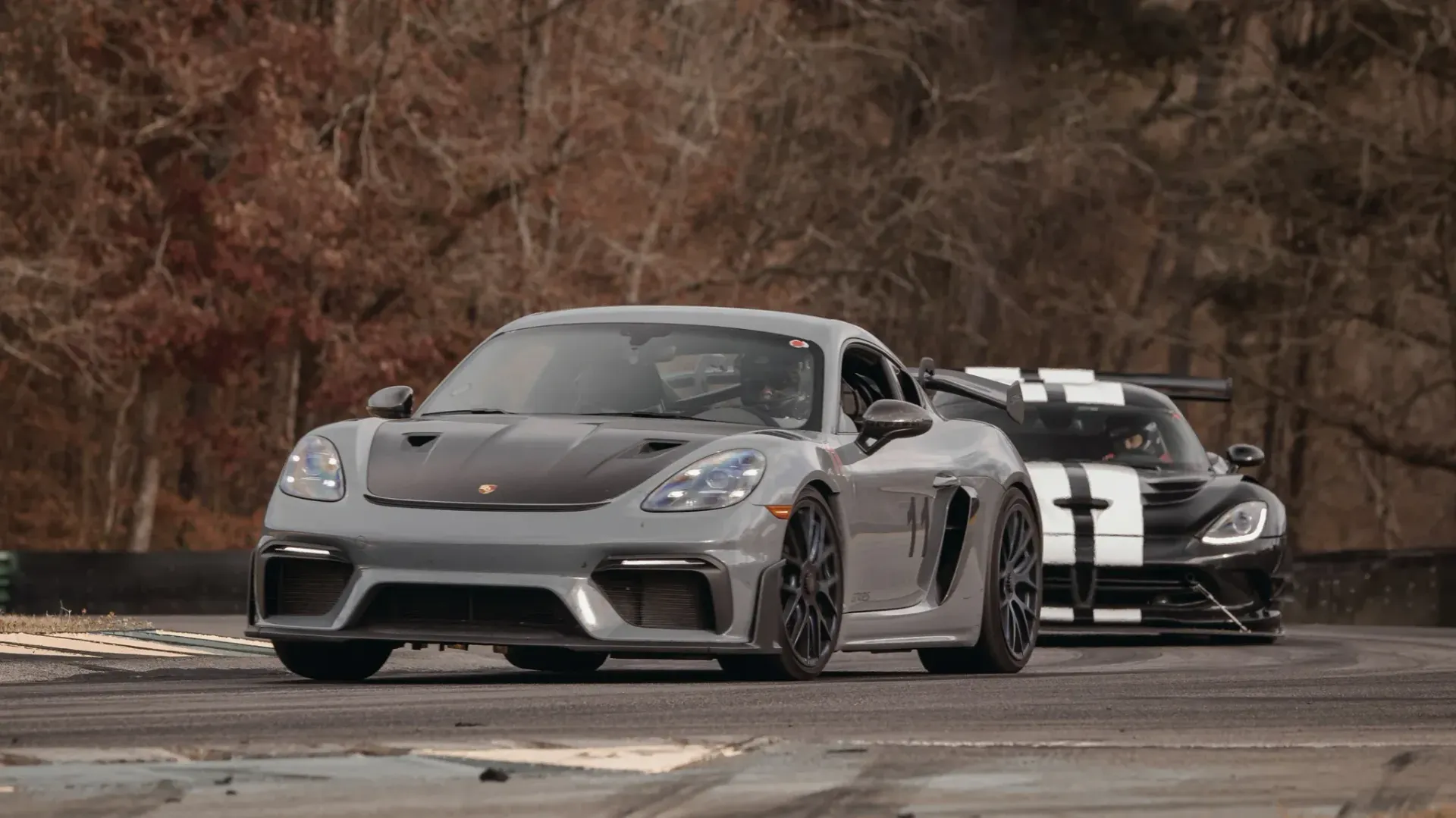 Two sports cars are driving down a road next to each other.