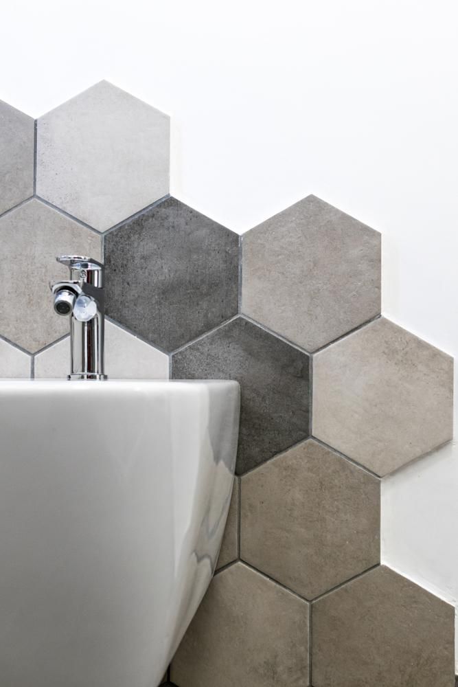 A bathroom sink with hexagonal tiles on the wall.