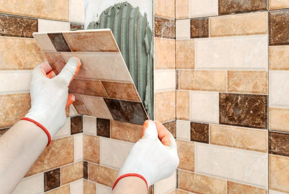 A Skilled Person Is Installing Tiles on A Wall — Peninsula Tiles in Umina Beach, NSW
