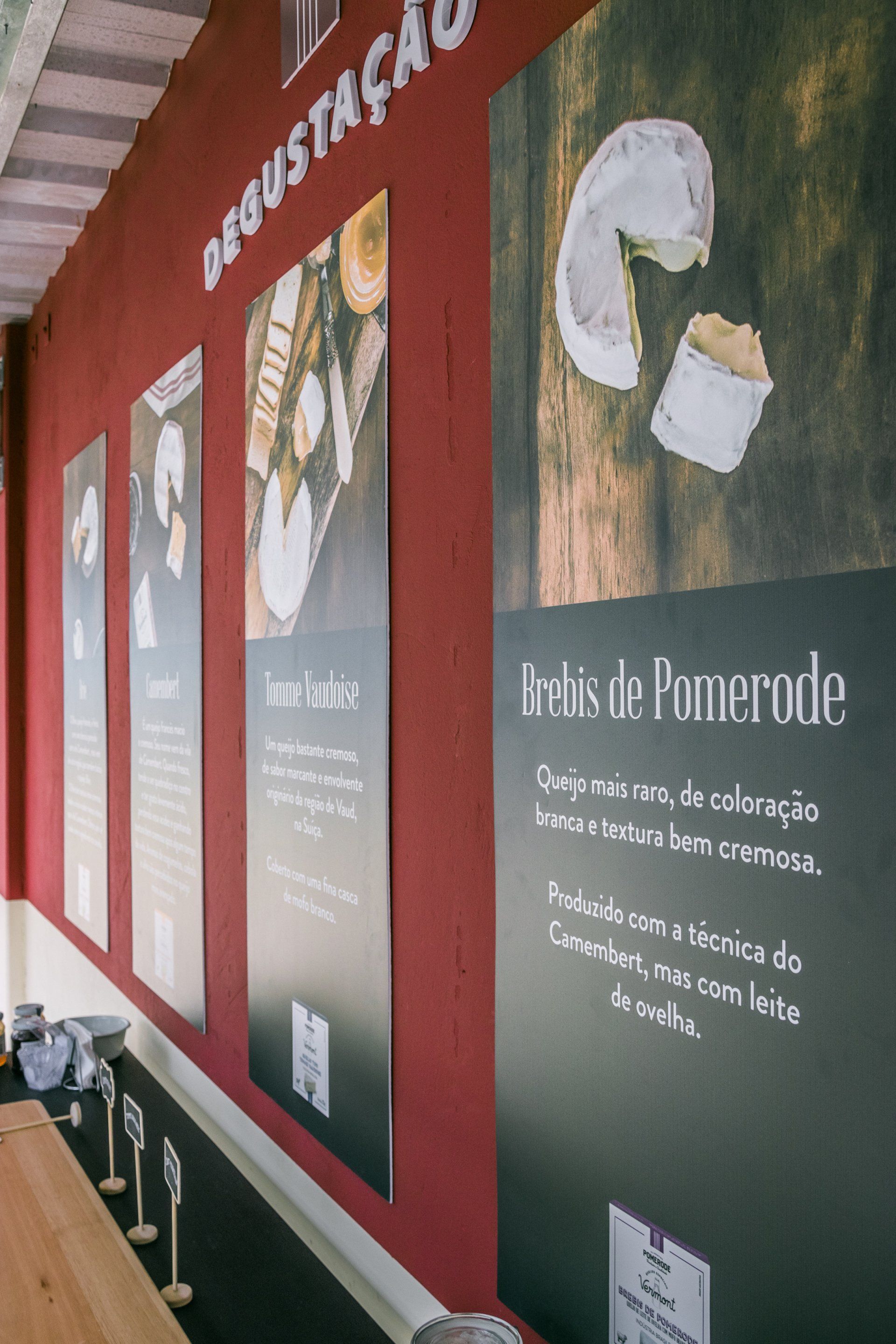 Uma fileira de pôsteres está pendurada em uma parede vermelha.