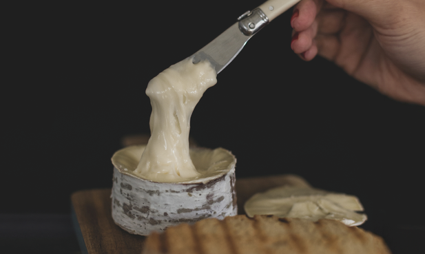 Uma pessoa está segurando uma colher em um pote de queijo.