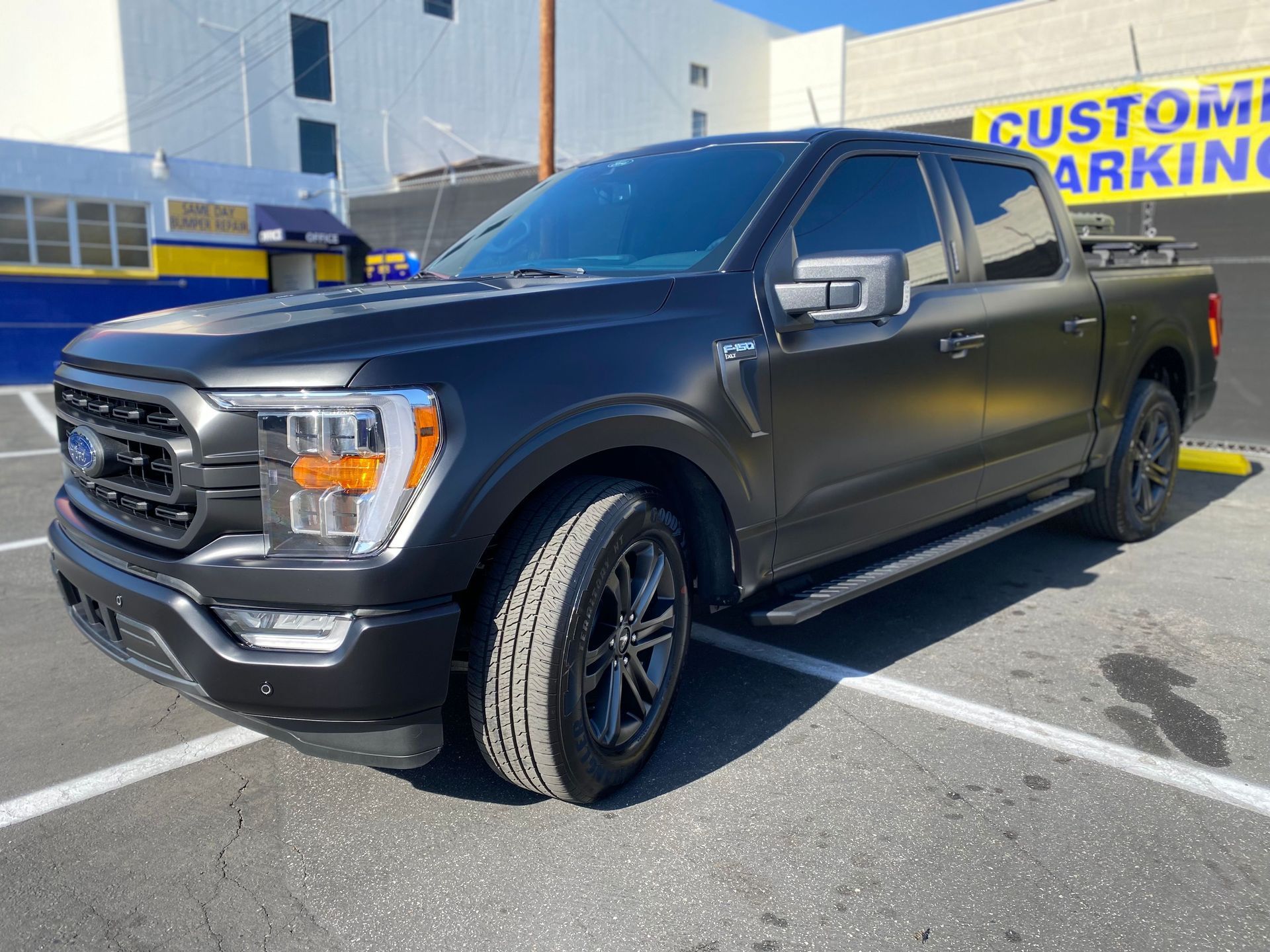 A black truck is parked in a parking lot in front of a building.