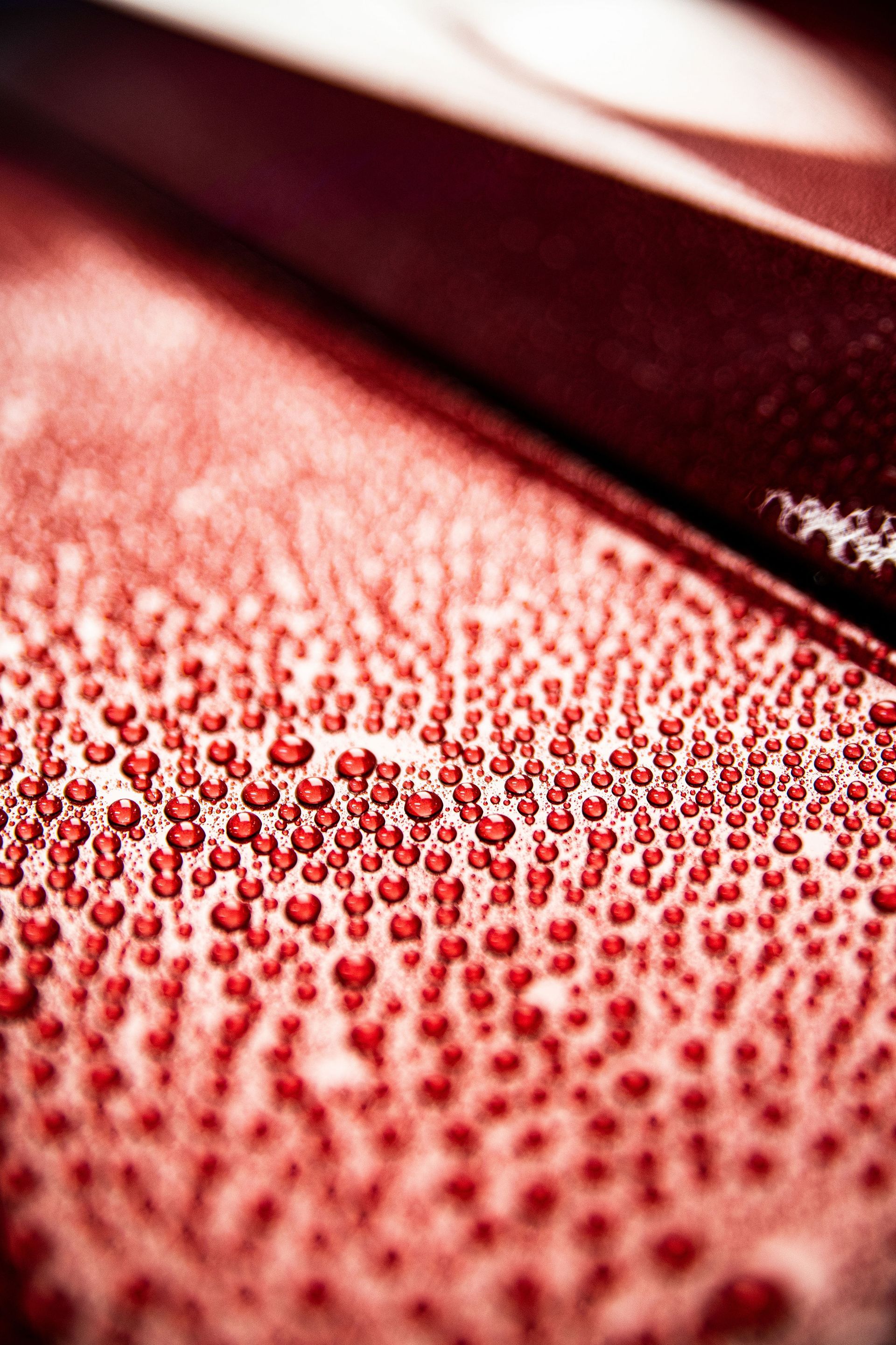 A close up of a red surface with water drops on it.