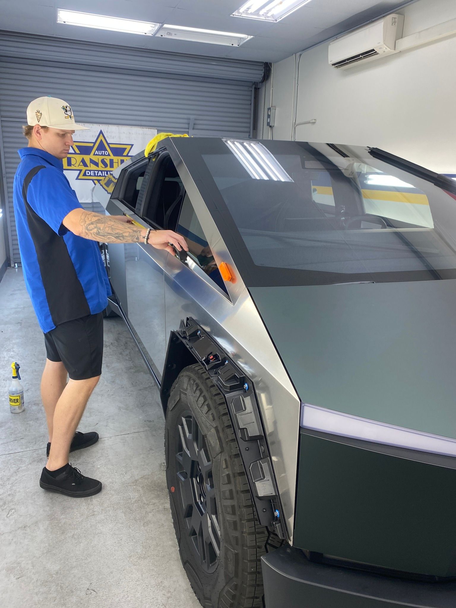 A man is standing next to a tesla cybertruck in a garage.