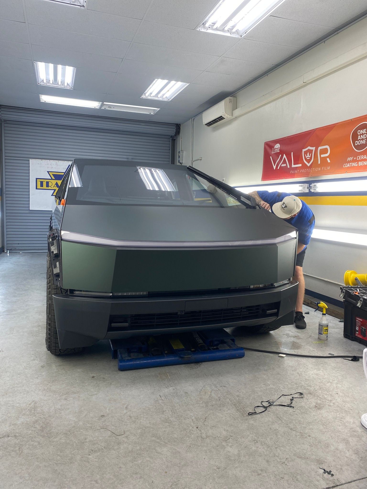 A man is working on a tesla cybertruck in a garage.