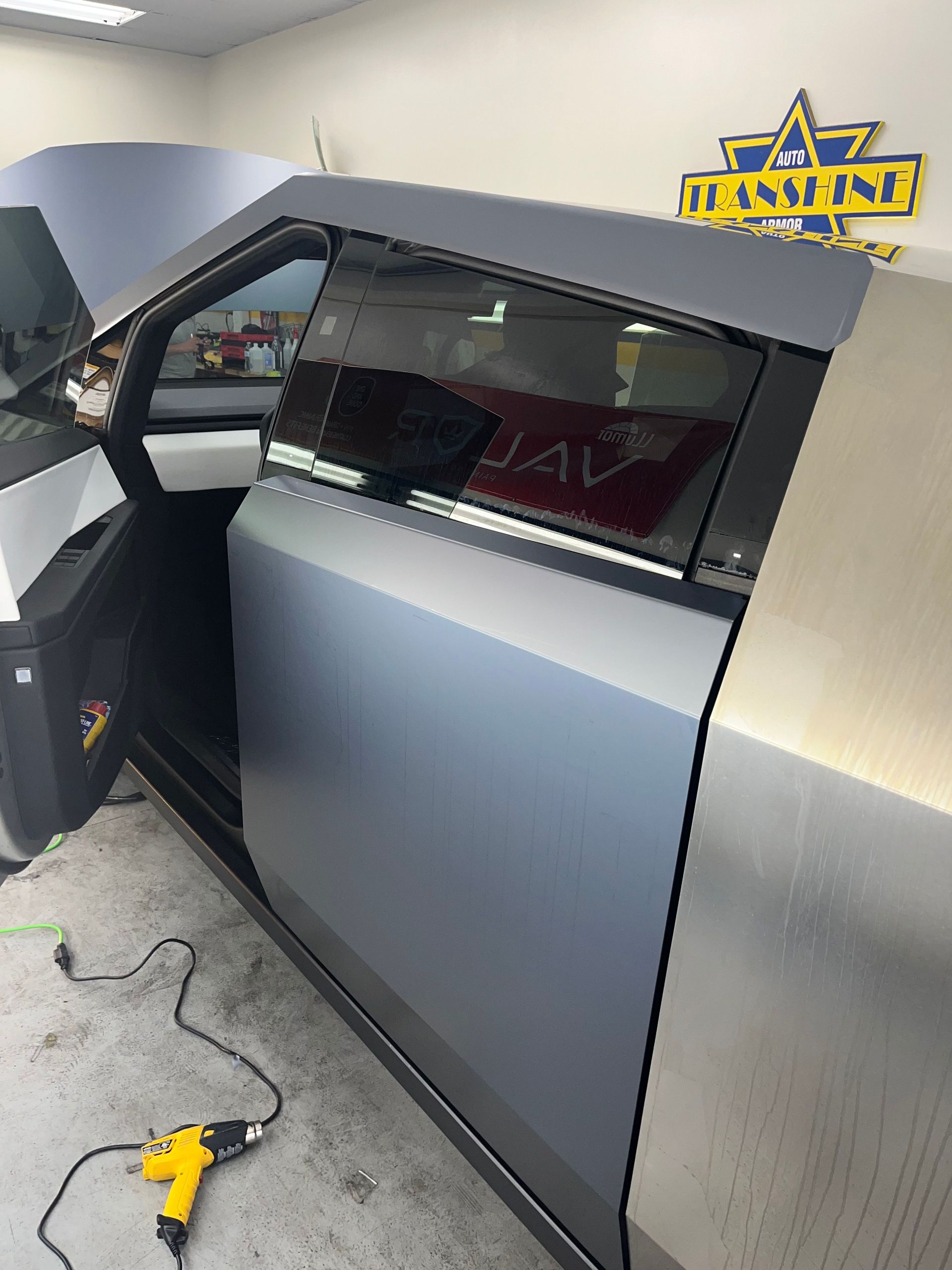 A car is being wrapped in aluminum foil in a garage.