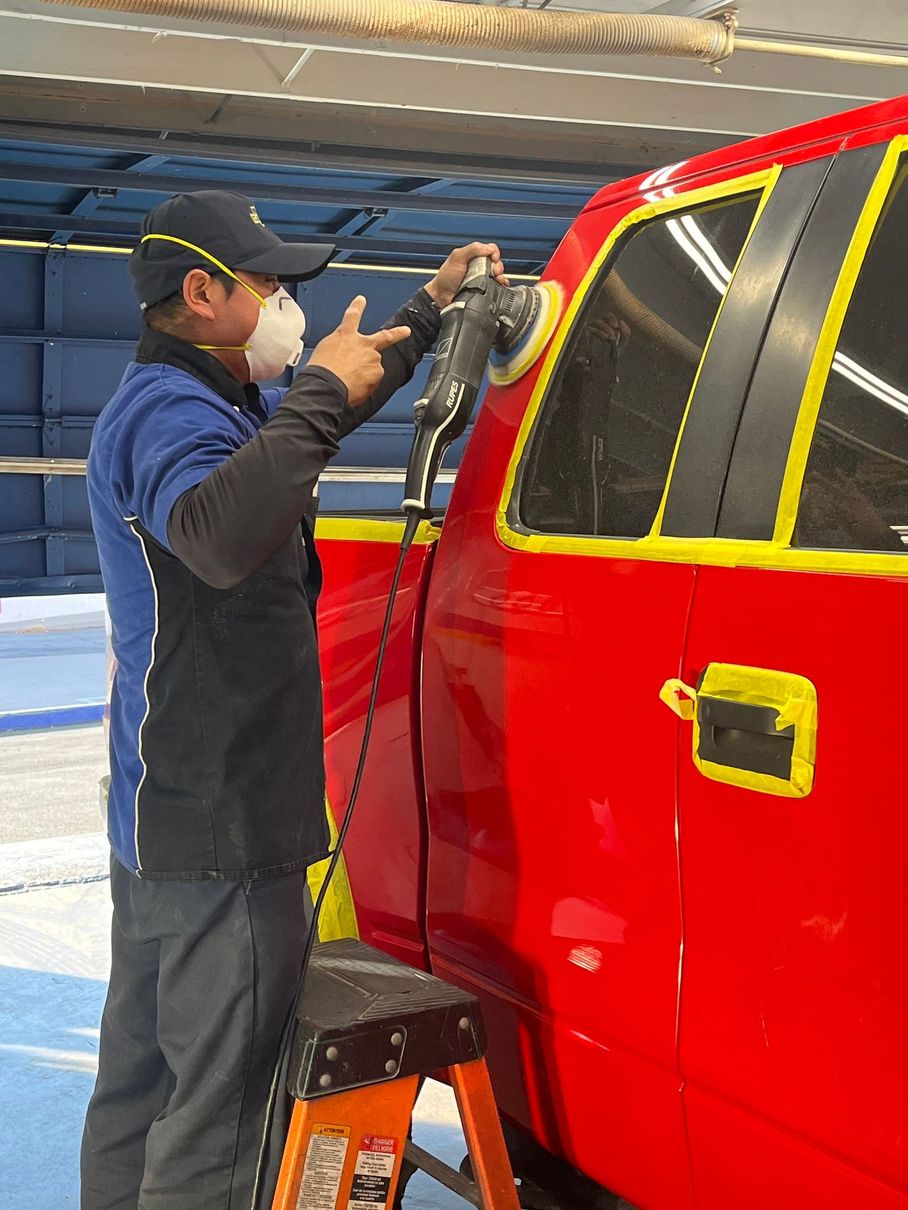 A man wearing a mask is polishing a red truck.