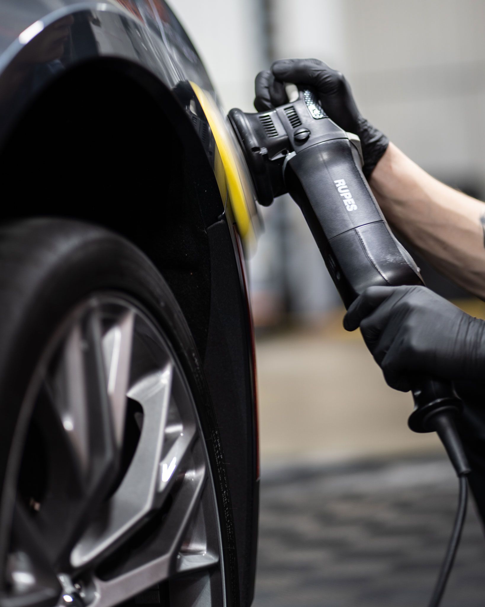 A person is polishing a car with a machine that says bmw on it