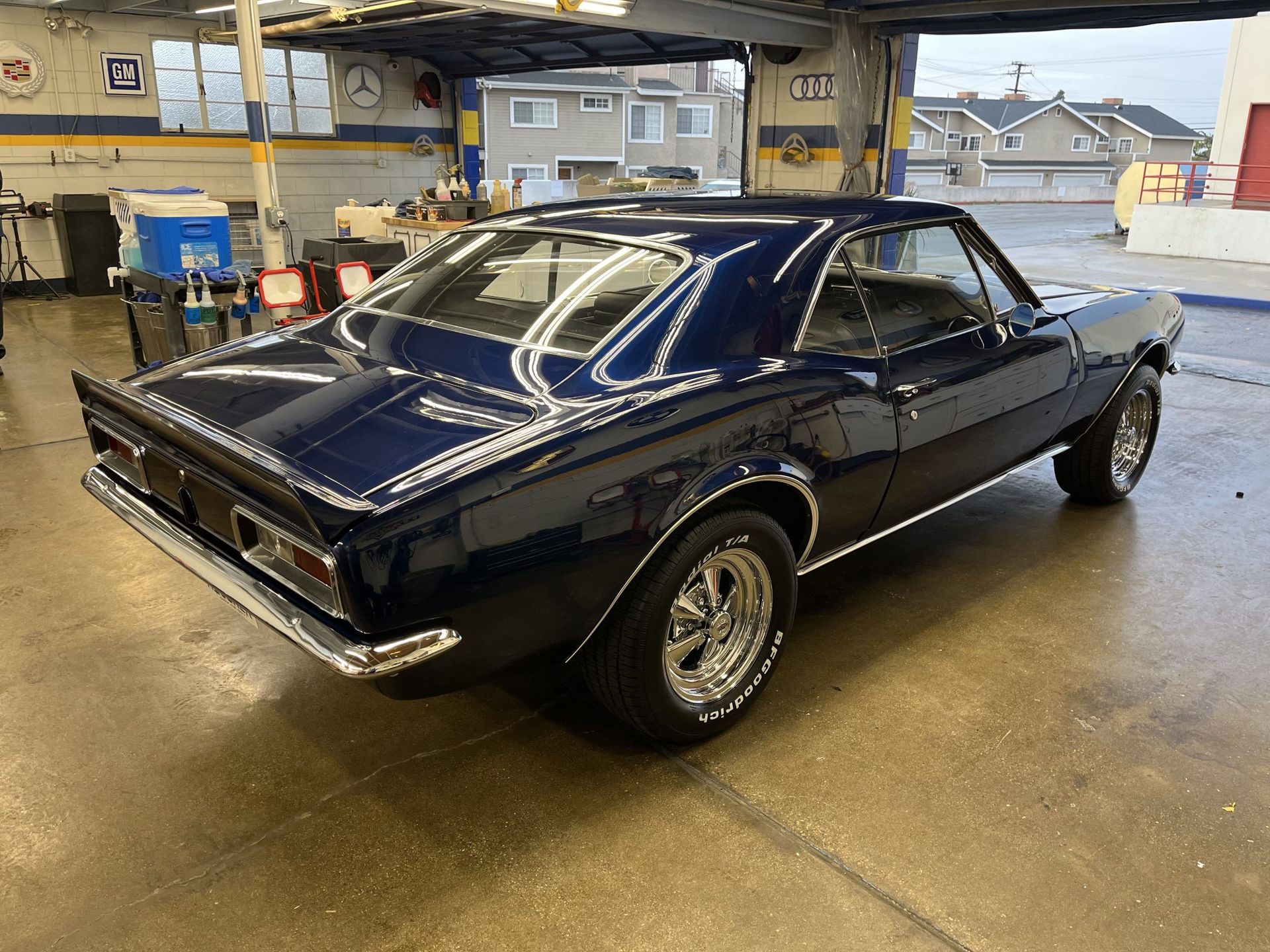 A blue muscle car is parked in a garage.