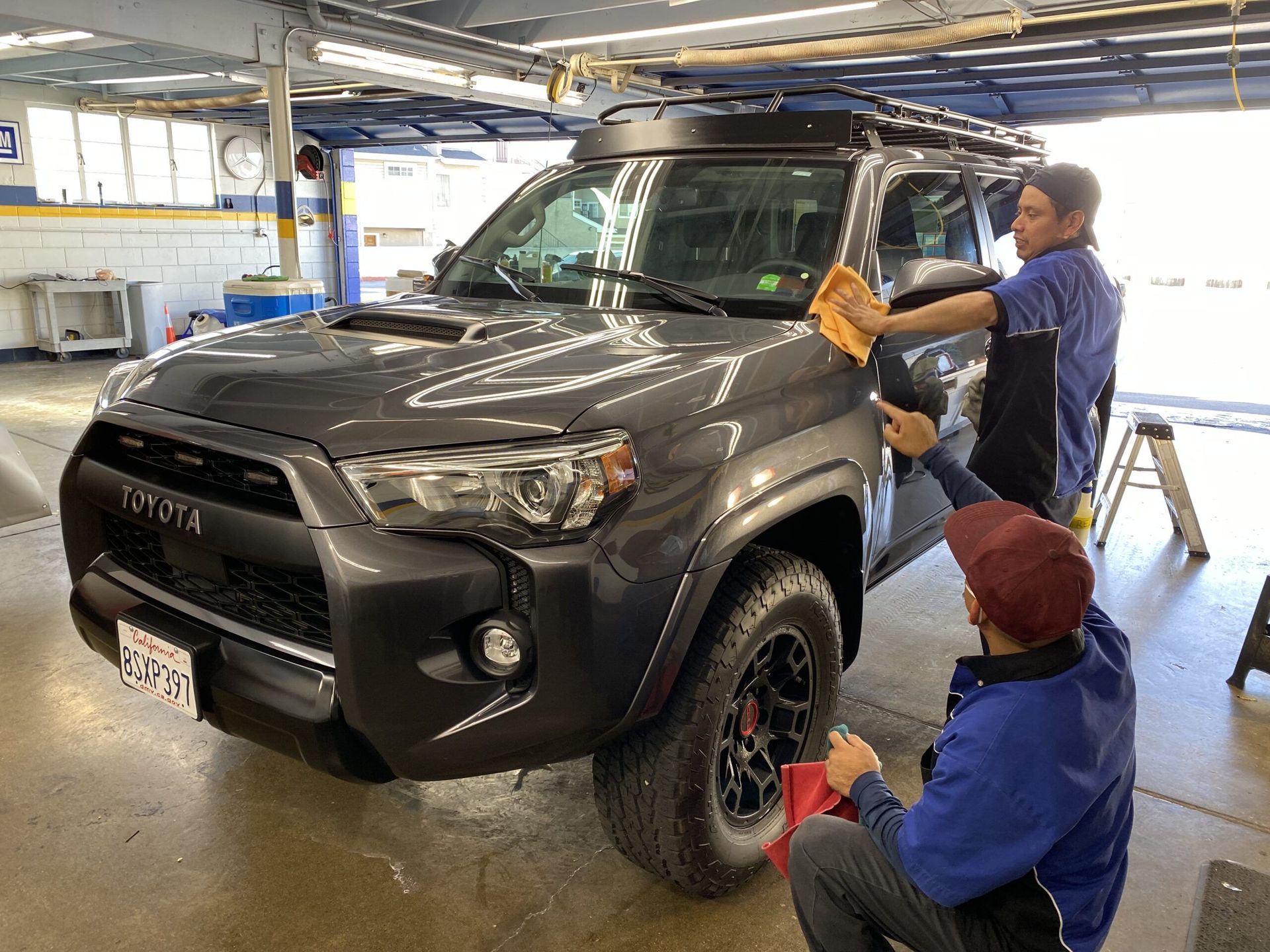Two men are cleaning a toyota 4runner in a garage.