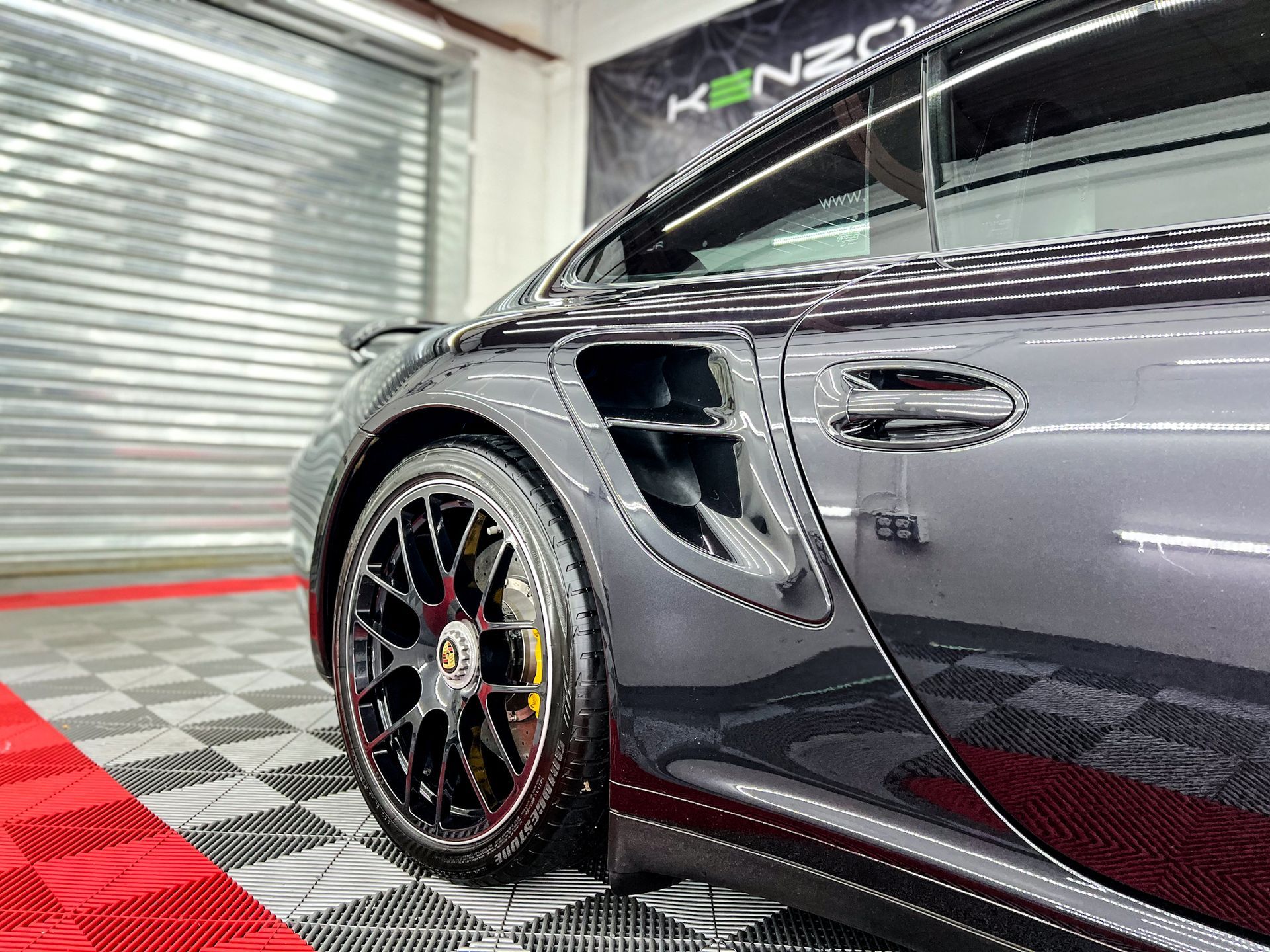 A gray sports car is parked in a garage.