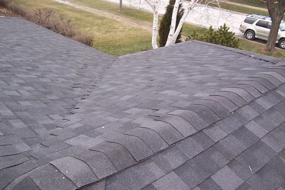 A close up of a roof with a car parked in the background
