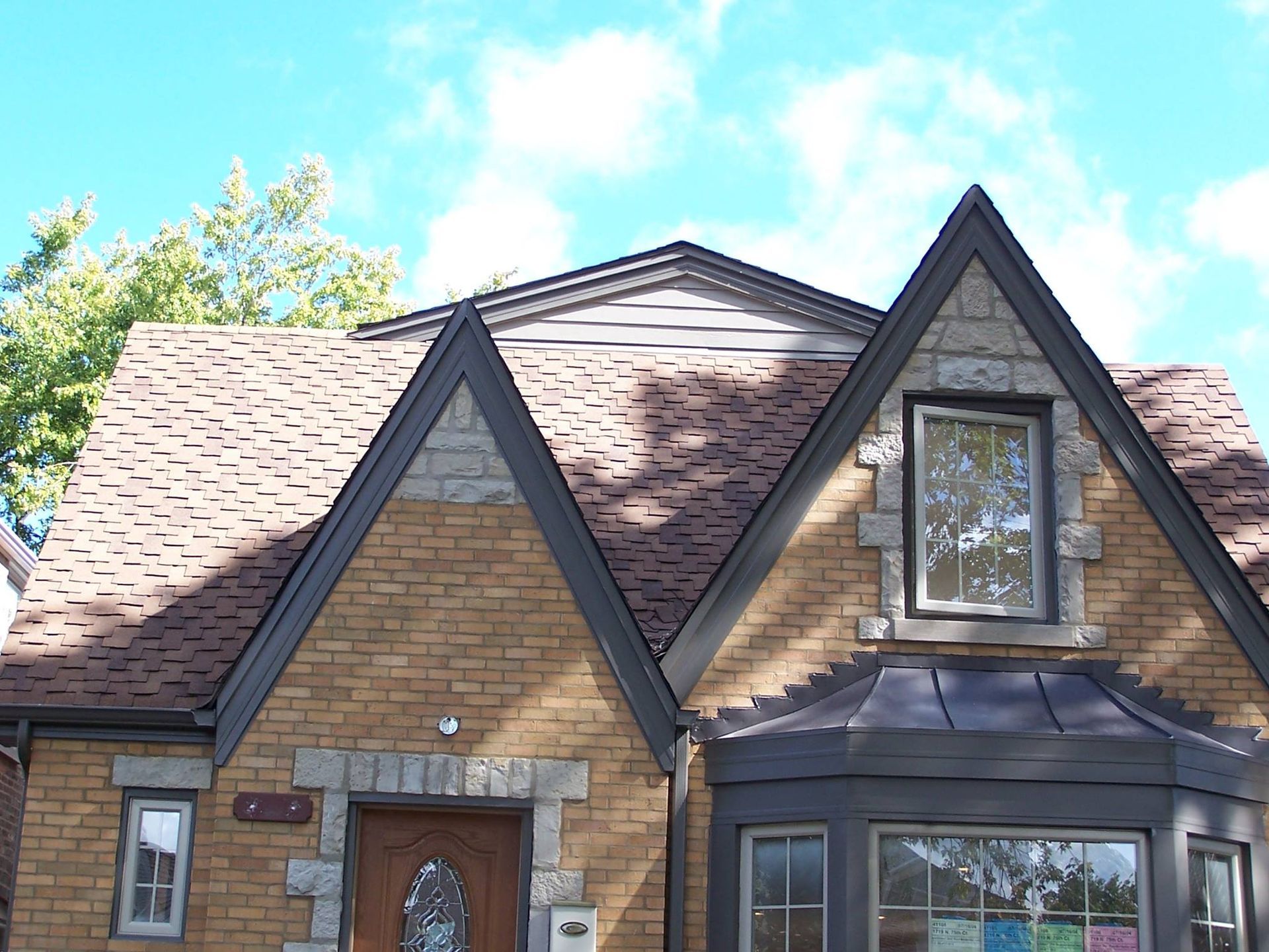A brick house with a brown roof and a bay window