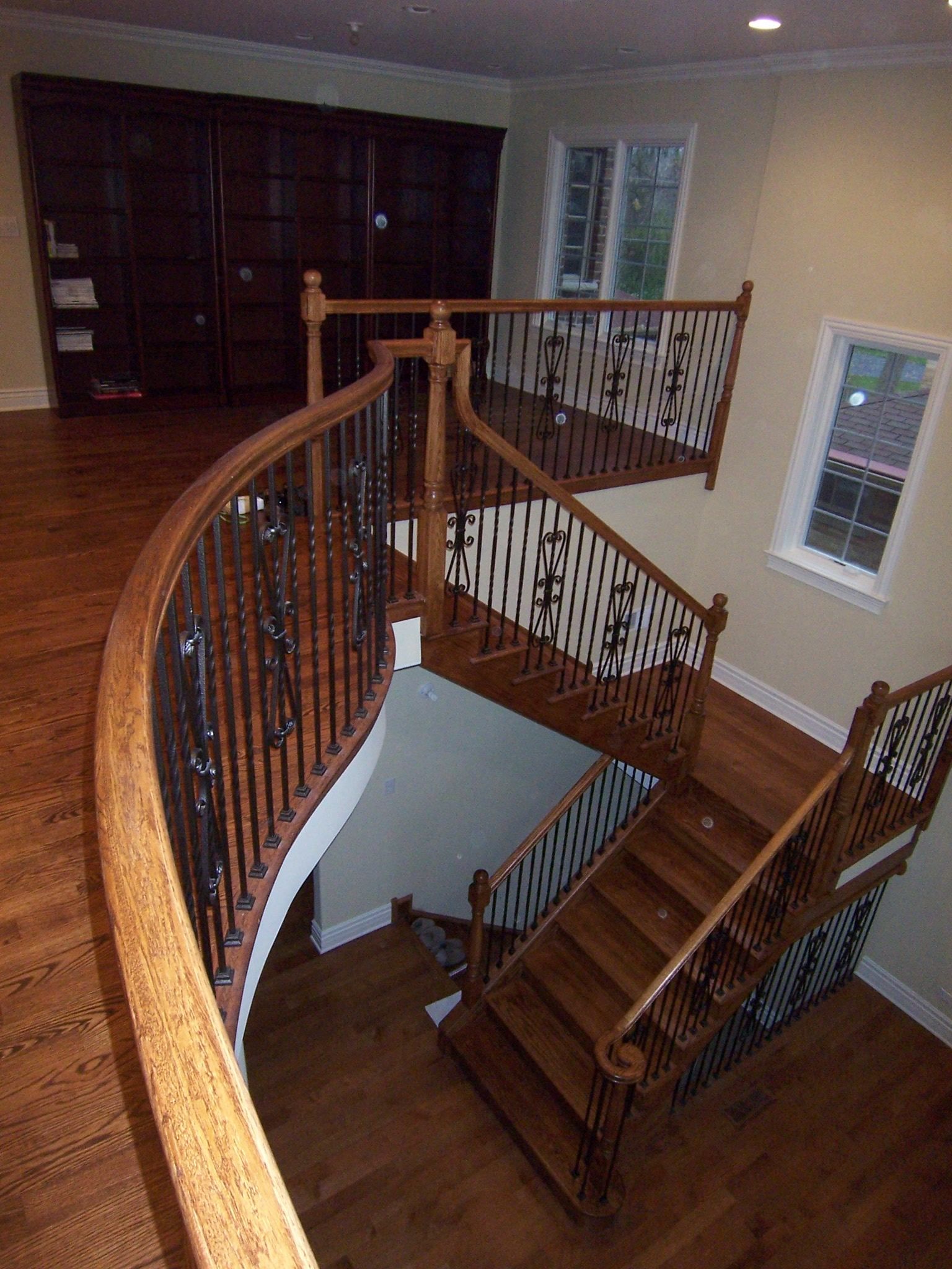A curved wooden staircase with a wrought iron railing