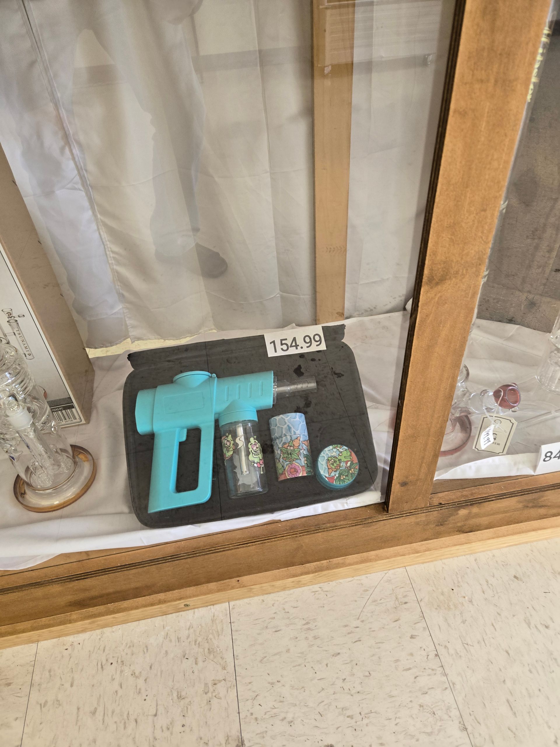 Display case with a teal toy gun, shot glasses, and a coaster, priced at $58.00.