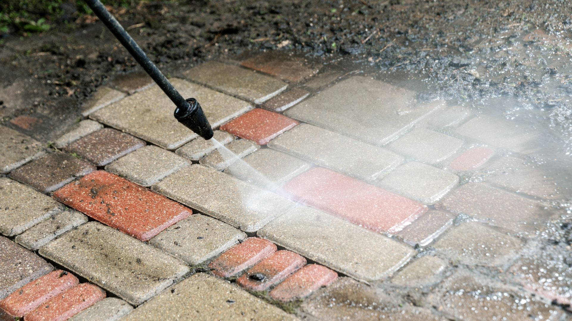 Pressure washing a brick patio; water spraying from a nozzle.