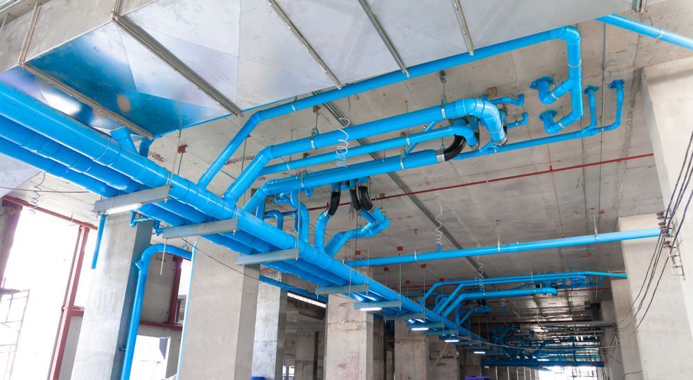 A Bunch of Blue Pipes Are Hanging From the Ceiling of a Building — Hoges Plumbing In Helensburgh, NSW
