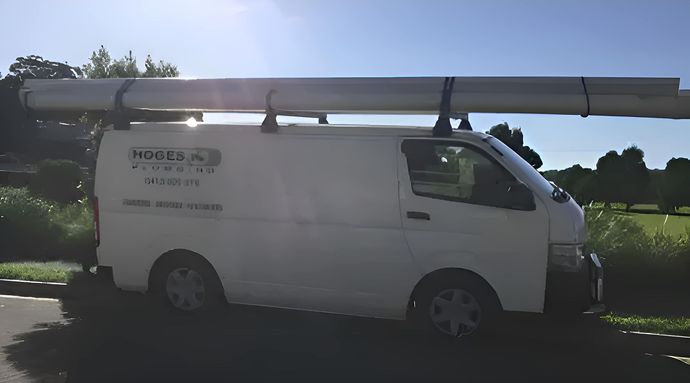 A White Van With a Large Pipe on Top of It — Hoges Plumbing In West Wollongong, NSW