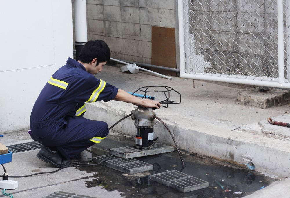 A Man is Working on a Pipe — Hoges Plumbing In West Wollongong, NSW