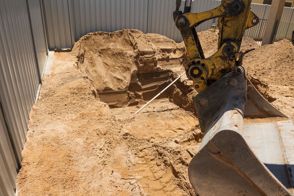 A Yellow Excavator is Digging a Hole for a Pool Shell — Hoges Plumbing In West Wollongong, NSW