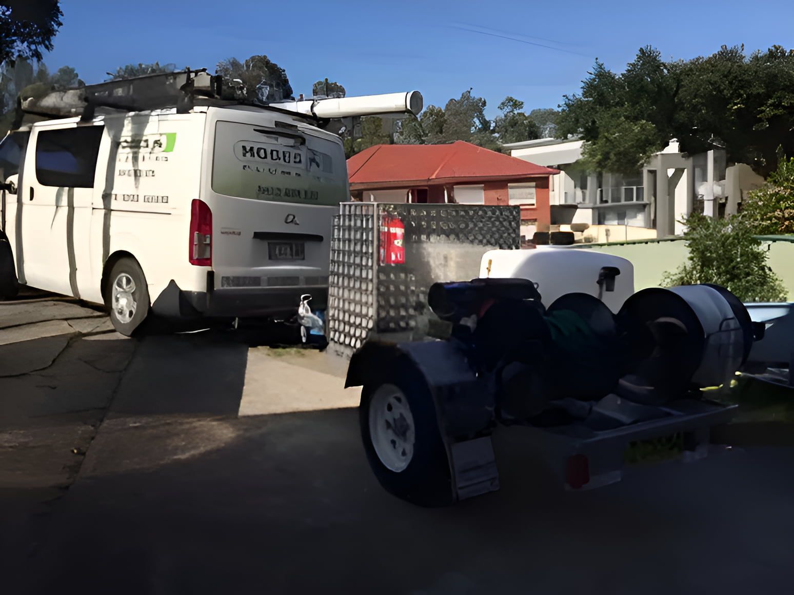 A White Van is Parked in a Driveway Next to a Trailer — Hoges Plumbing In West Wollongong, NSW