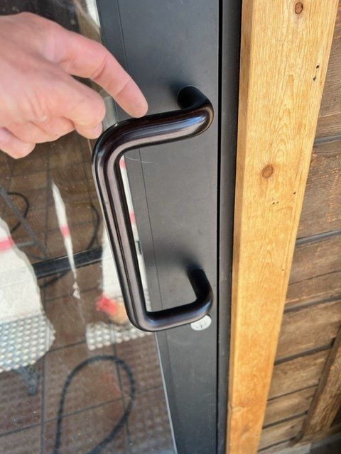 A person is opening a glass door with a black handle
