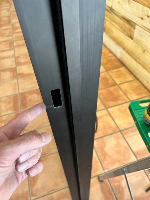 A person is pointing at a hole in a door frame.