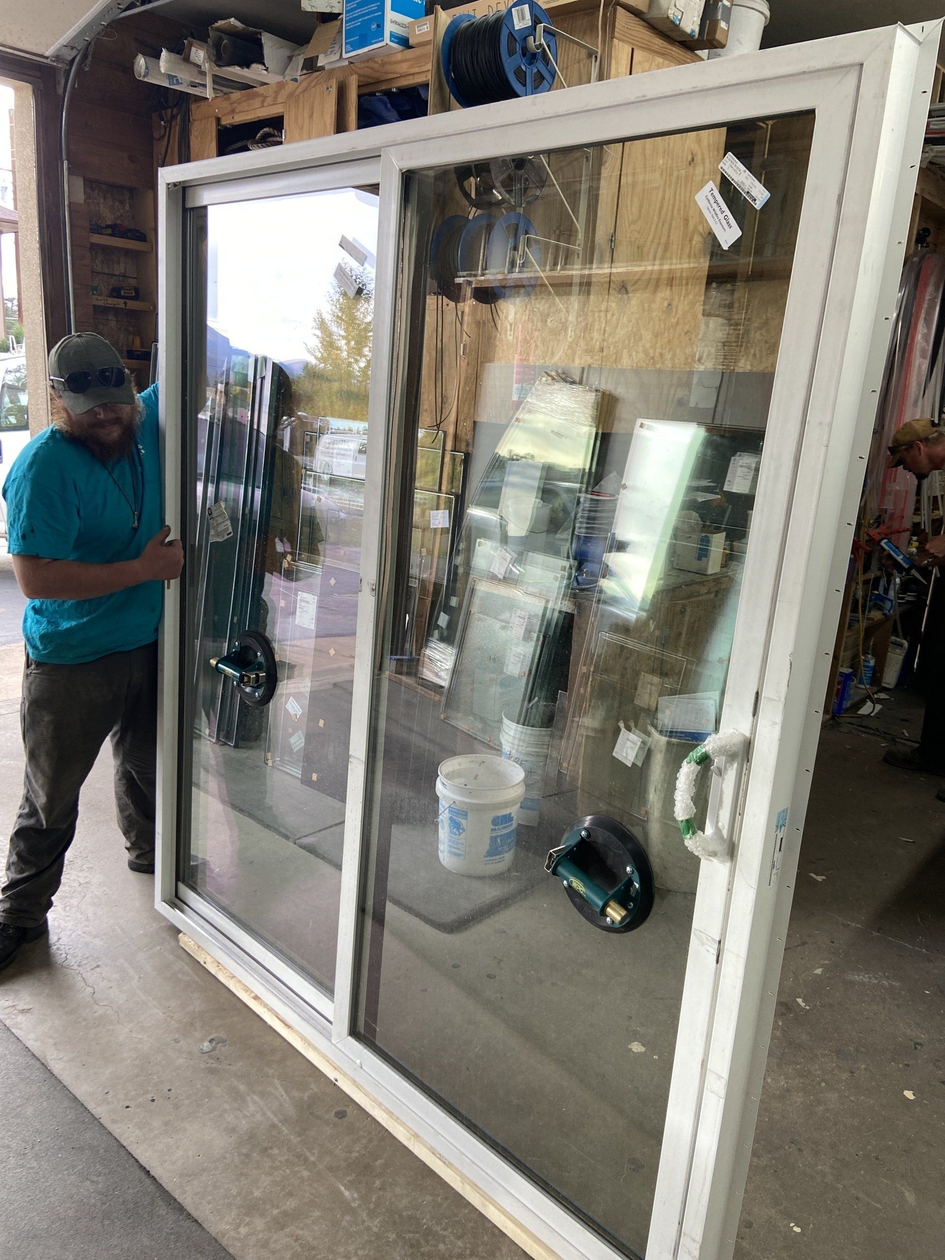 A man is lifting a sliding glass door in a garage.