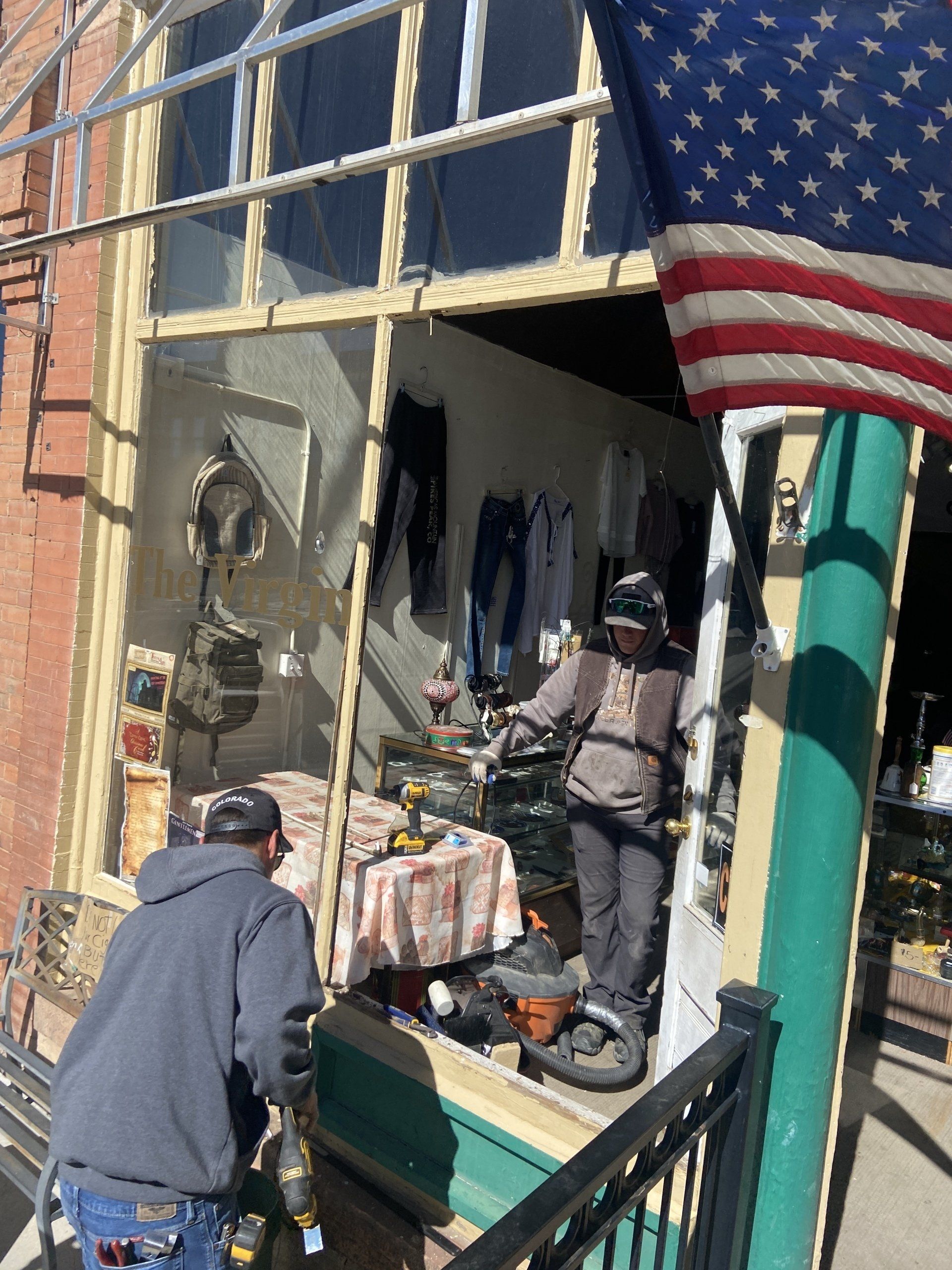 A man standing in front of a store with an american flag in the background