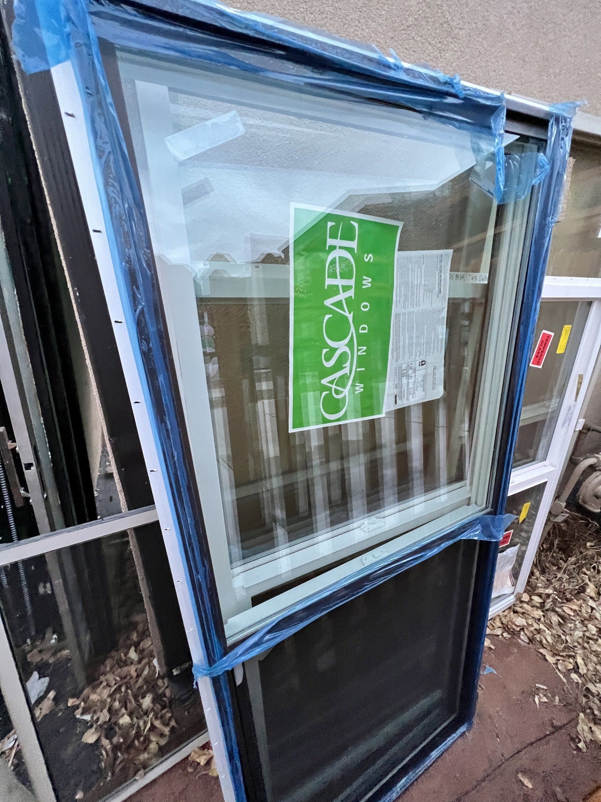 A window with a screen is sitting on top of a pile of windows.