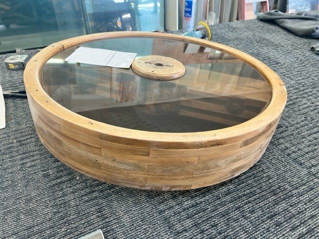 A wooden table with a glass top is sitting on a carpeted floor.