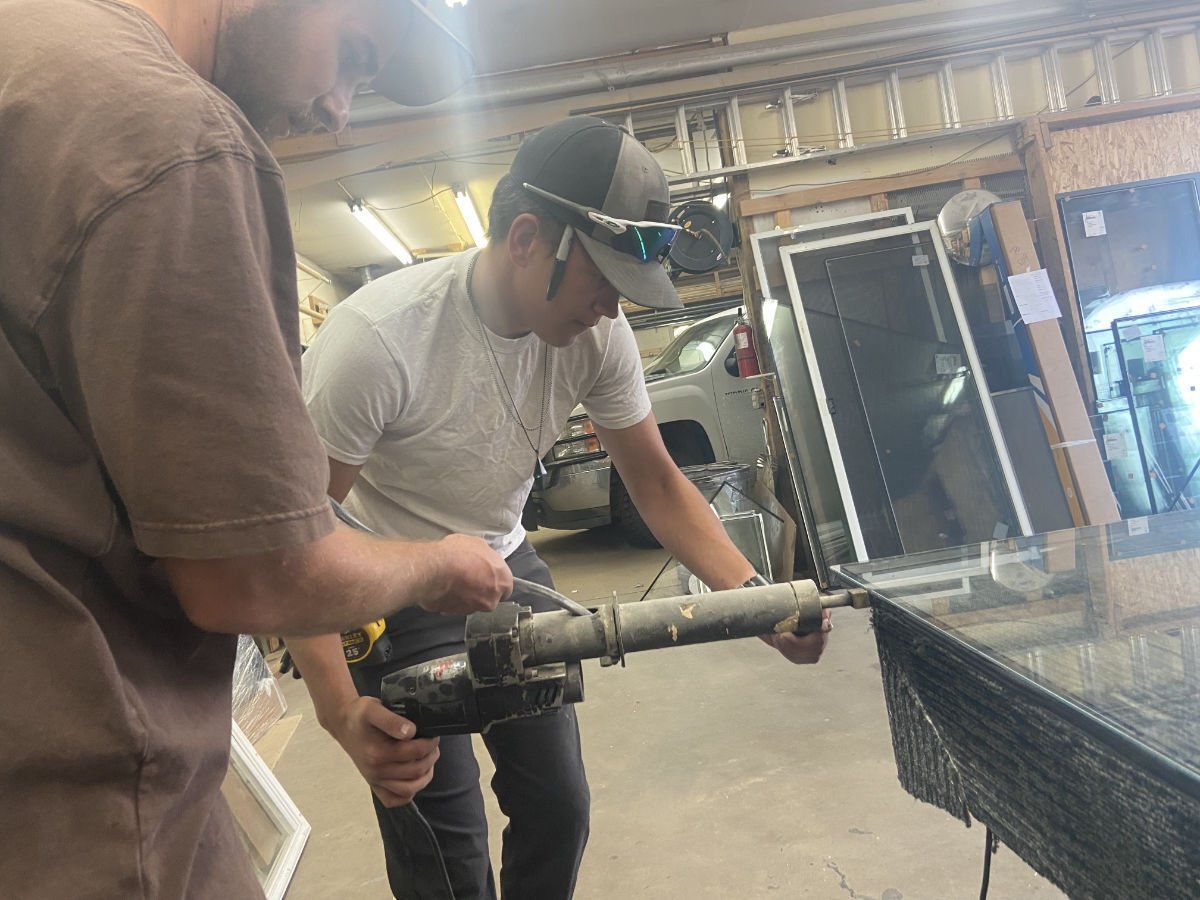 Two men are working on a piece of glass in a garage.