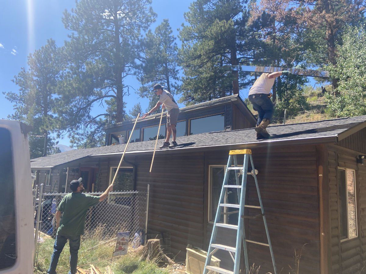 Two men are working on the roof of a house.