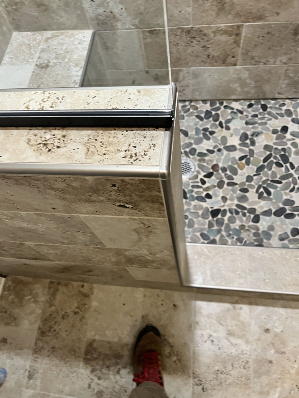 A person is standing in a bathroom next to a shower stall.