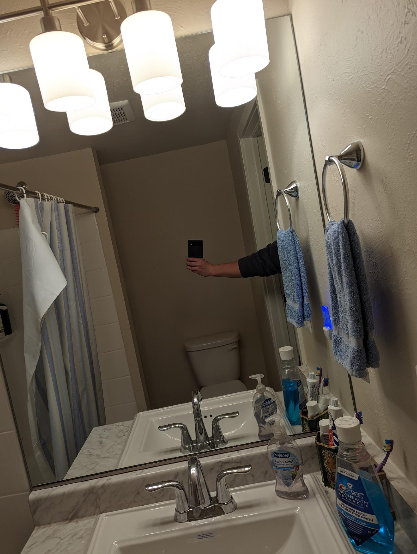 A person is taking a selfie in a bathroom mirror.