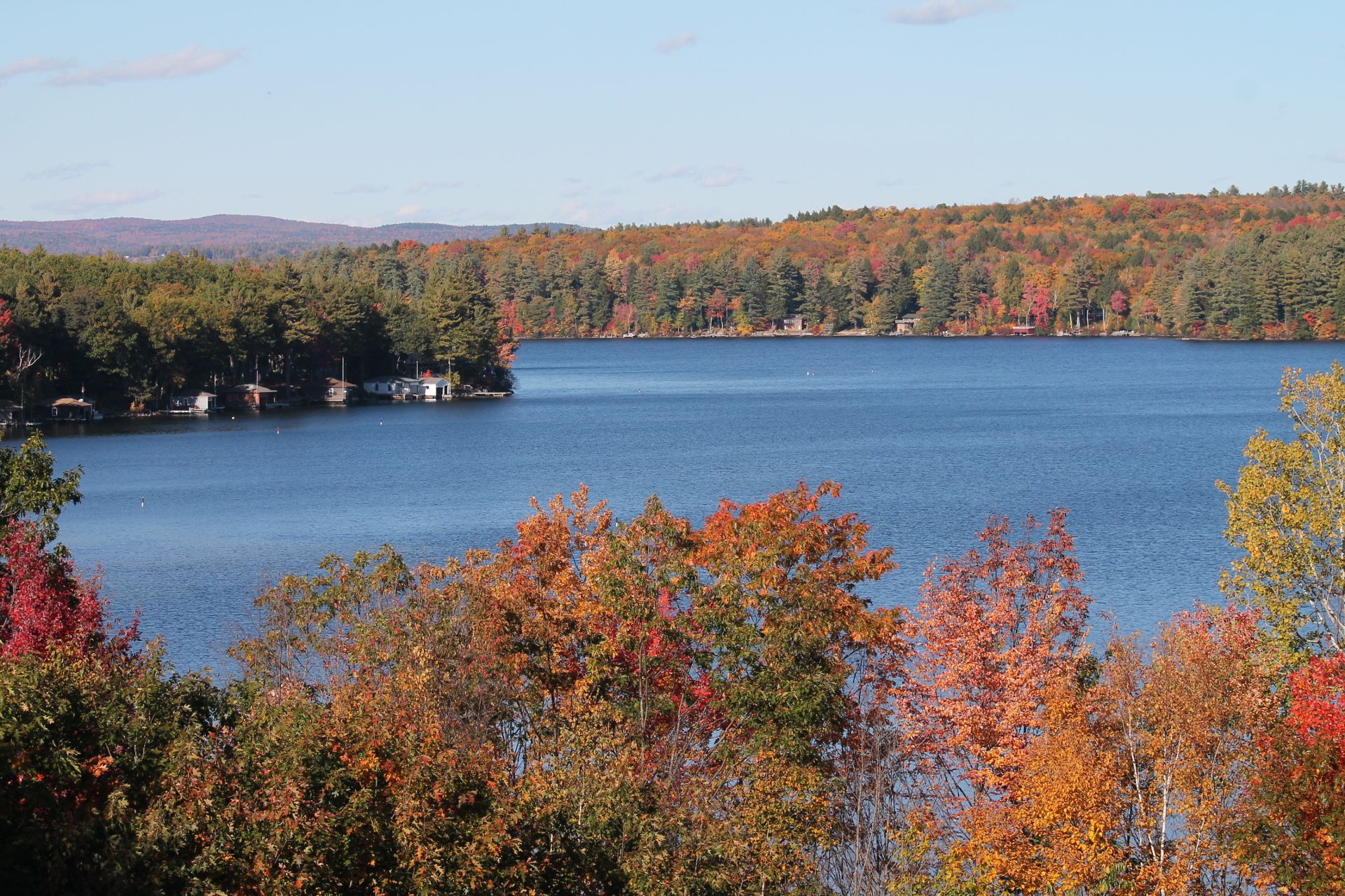 A serene lake surrounded by vibrant autumn foliage under a clear, blue sky.