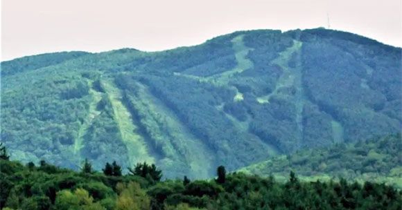 Green mountain with ski runs cut into it.