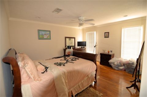 Bedroom with hardwood floor, ceiling fan, and two windows