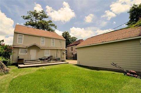 Two story house with garage and green yard with partially mowed grass