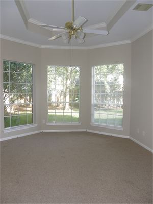 Bay windows in carpeted room with ceiling fan