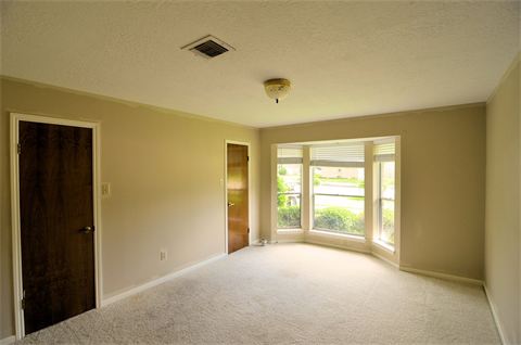 Carpeted room with bay windows and two doors