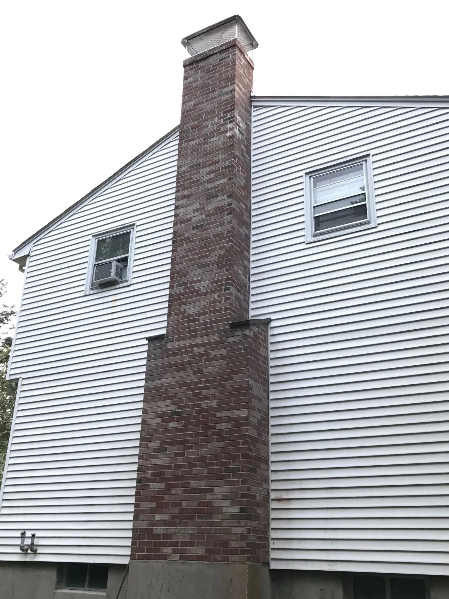 A white house with a brick chimney on the side.