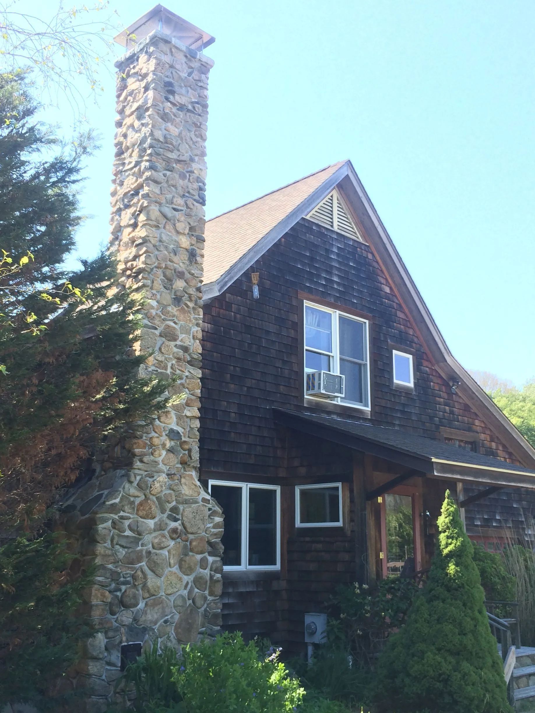 A house with a large stone chimney on the side.