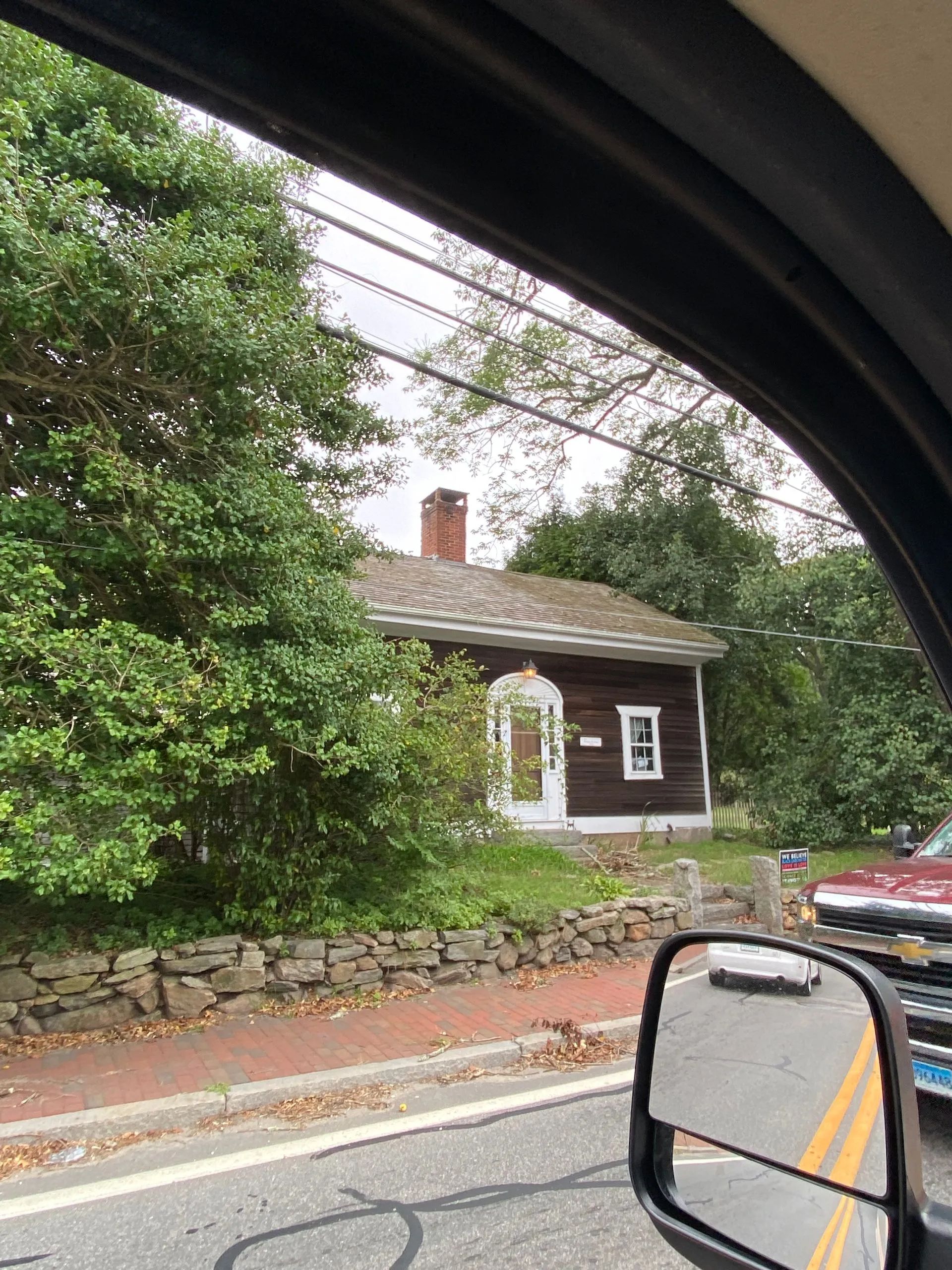 A car is driving down a road with a house in the background.