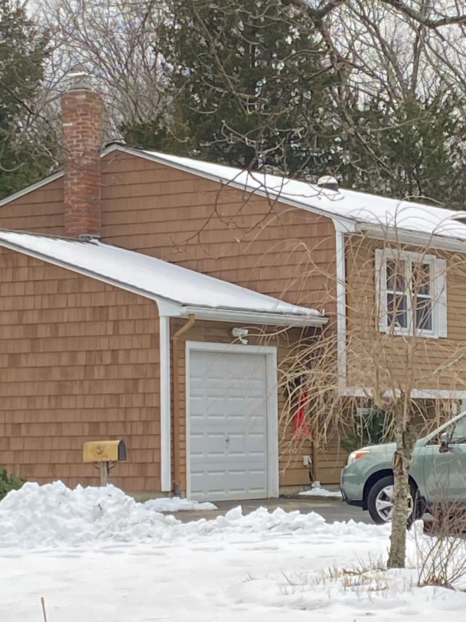 A car is parked in front of a house in the snow.