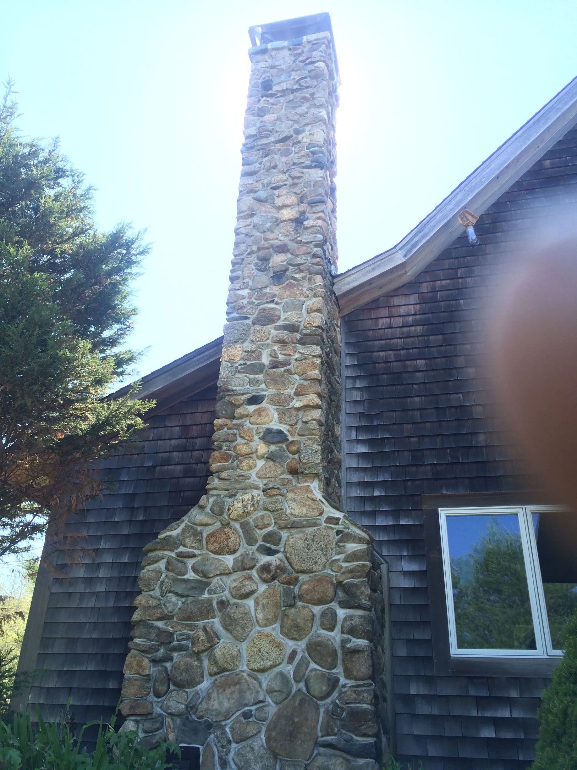 A large stone chimney on the side of a house.