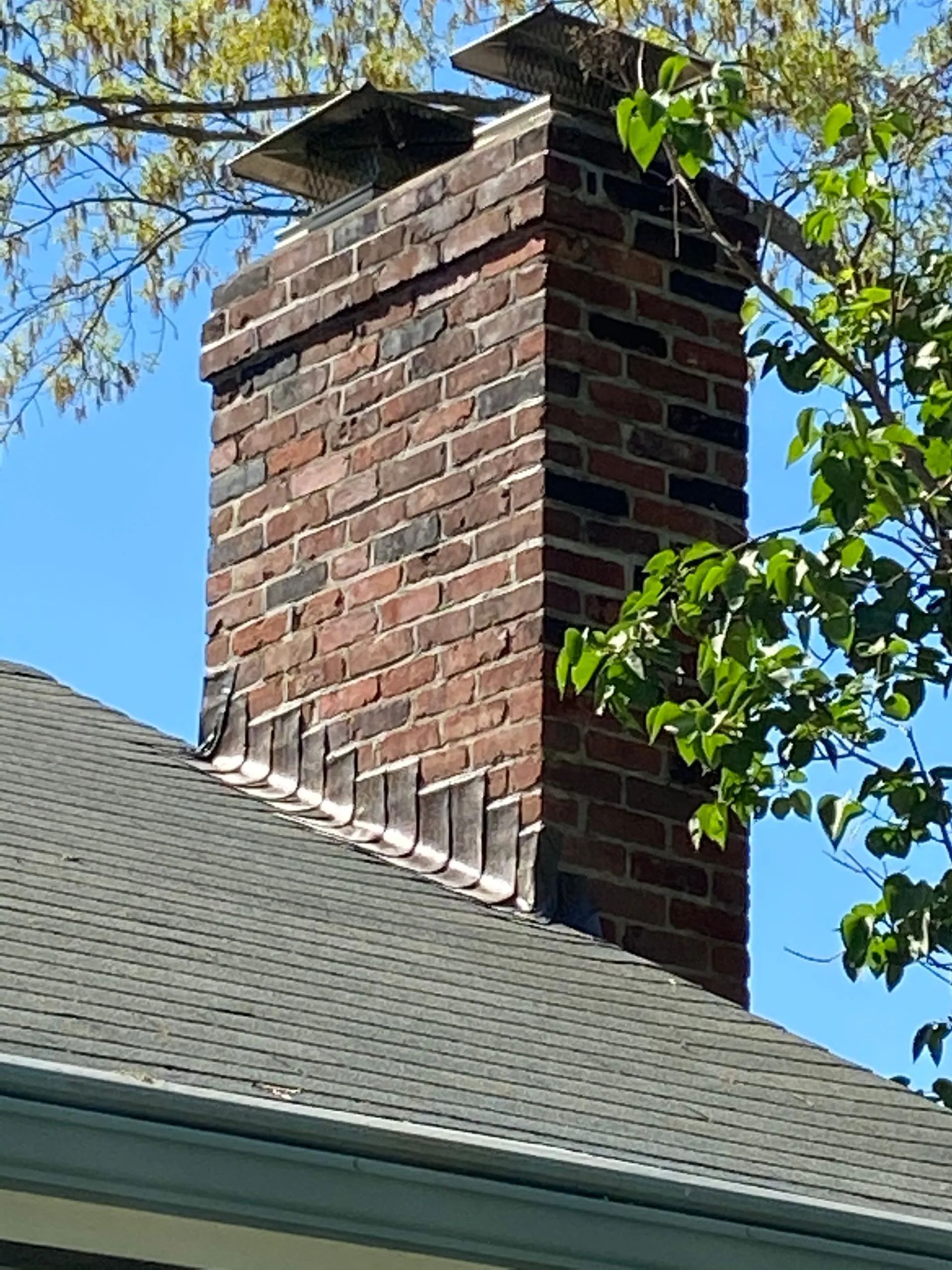 A brick chimney is on the roof of a house.