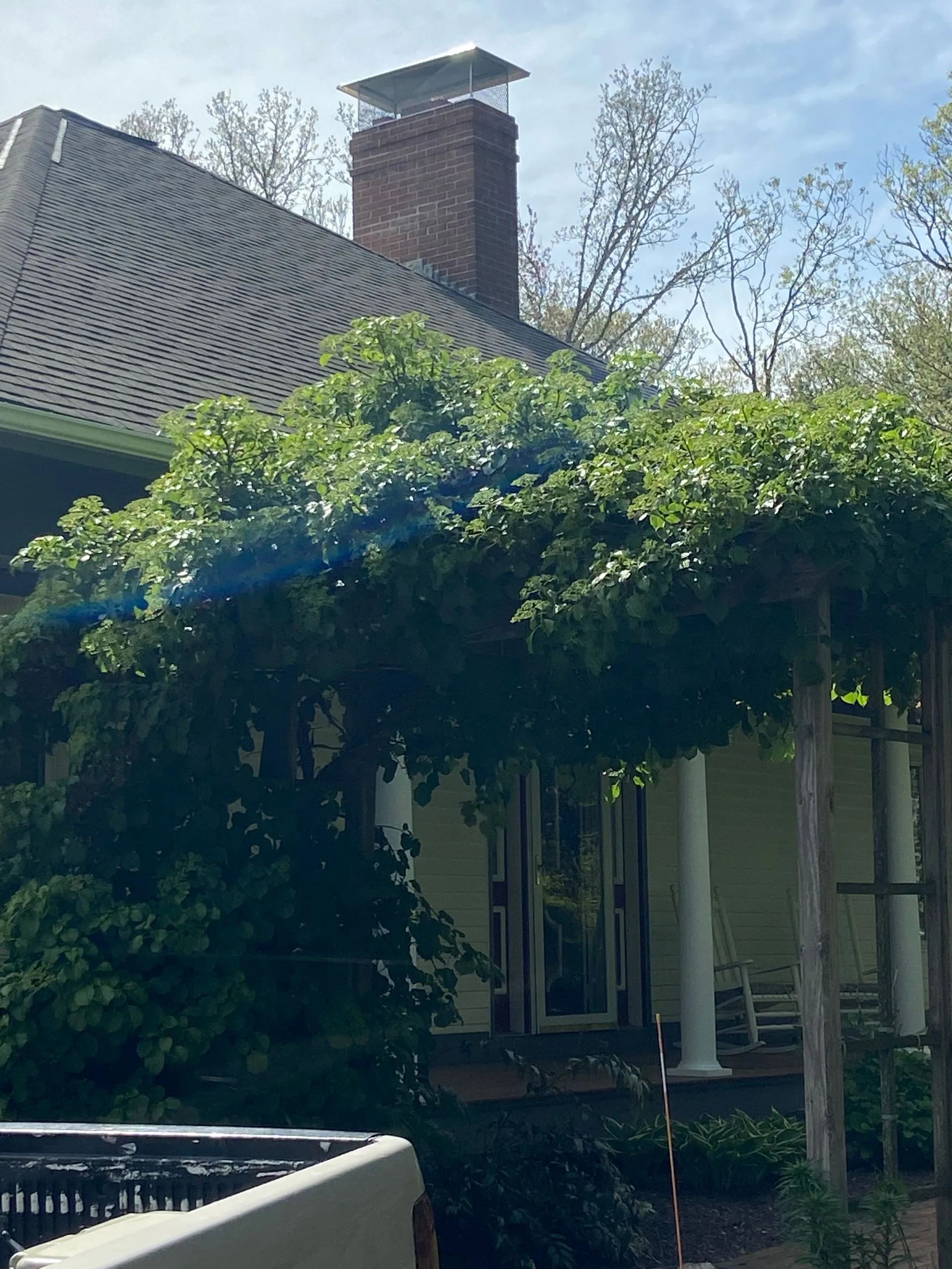 A house with a brick chimney and a pergola on the porch.