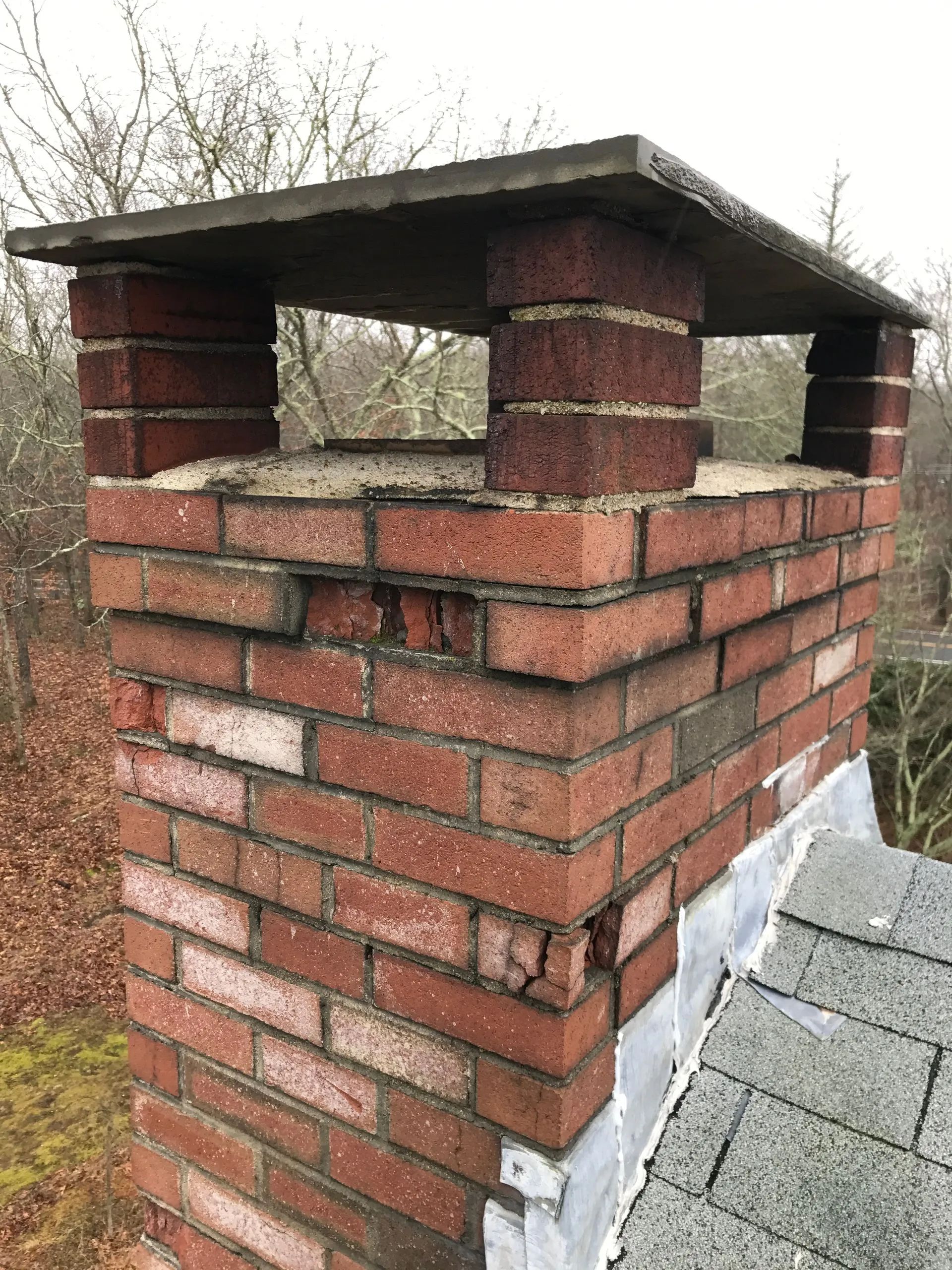 A brick chimney on top of a roof with a wooden top.